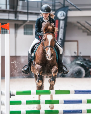 Zawodniczka na koniu przeskakuje przeszkodę podczas zawodów jeździeckich
