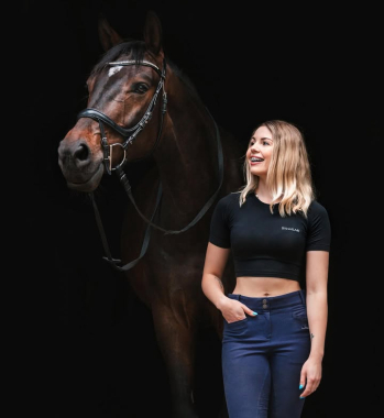 Kobieta w czarnym stroju stoi przy ciemnobrązowym koniu na czarnym tle